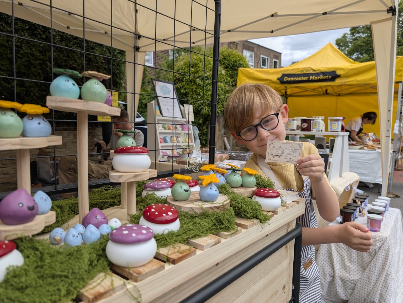 Oliver with handmade Tree Spirits at a market stall.